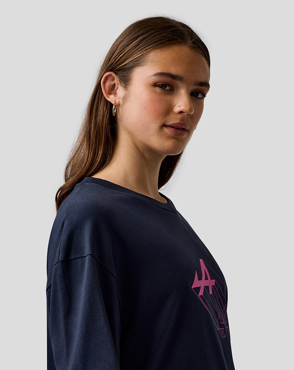 Female model wearing navy relaxed fit T shirt with pink Alpine graphic on chest and branding on sleeve and upper back.