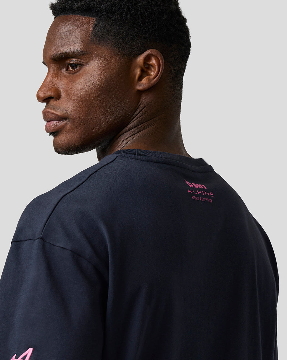 Rear view of a man in navy T shirt with pink Alpine branding on upper back.