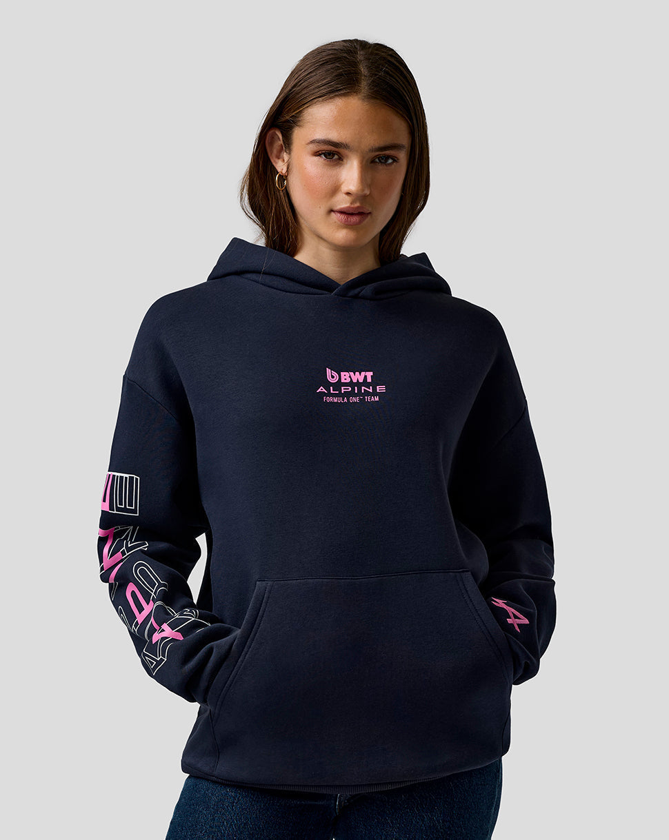 Front view of a model wearing a navy BWT Alpine hoodie with pink Alpine logo on the chest and sleeve graphics.