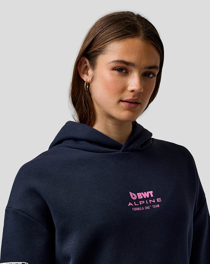 Woman wearing navy Night Sky hoodie with pink Alpine chest logo.