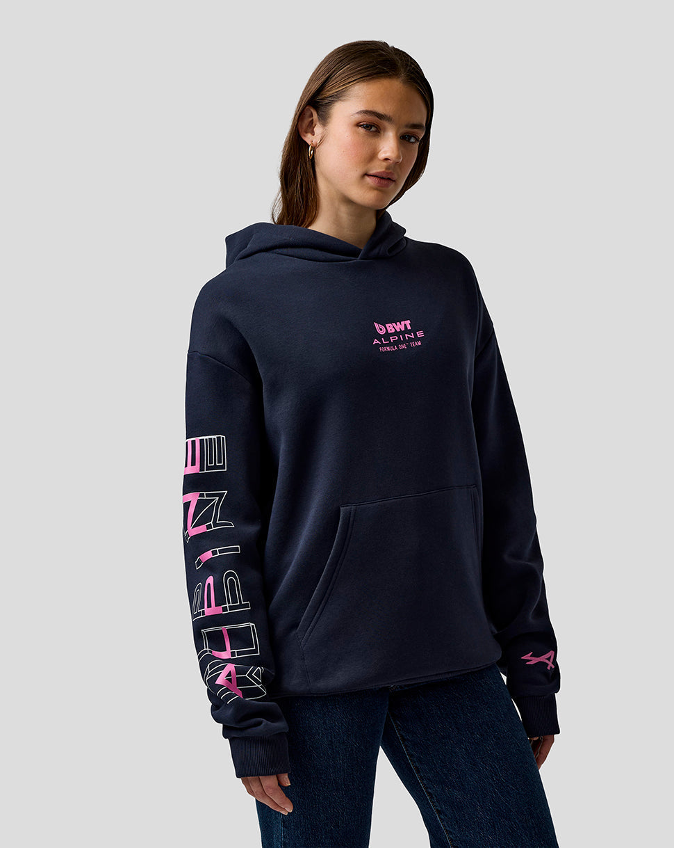 Woman in navy Night Sky hoodie with Alpine chest logo and large pink sleeve graphic and front kangaroo pocket.