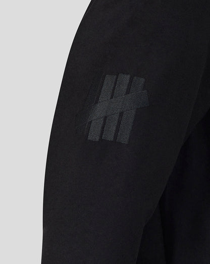 Black long-sleeve shirt with a logo on the sleeve against a light gray background