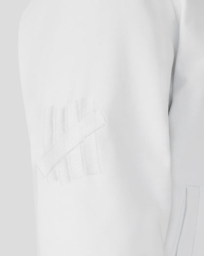 Close-up of a white dress with a subtle pattern on a light gray background