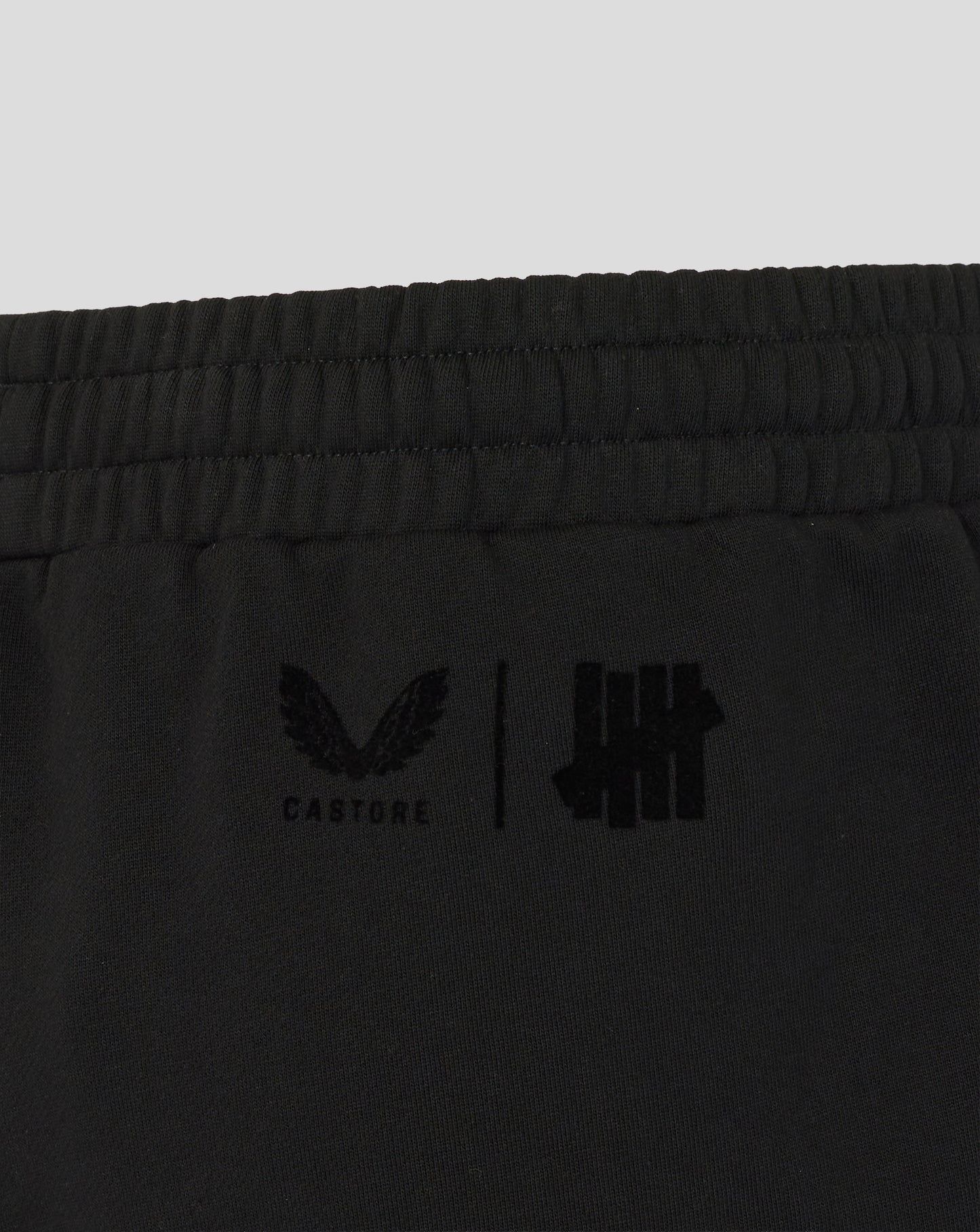 Black shorts with logos on a light gray background