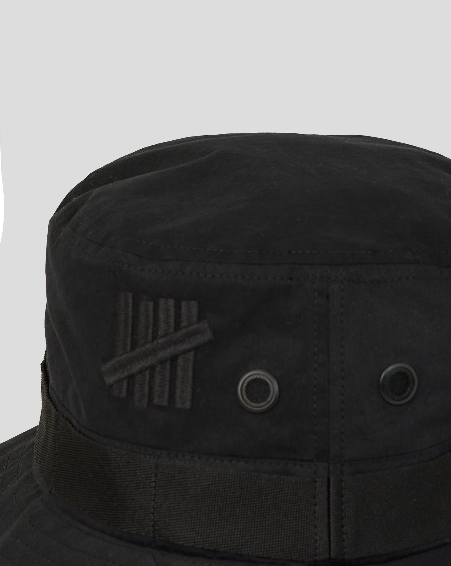 Black bucket hat with a brand logo on a light gray background