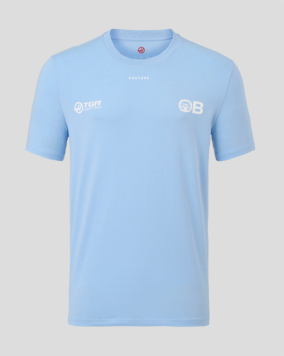 A light blue short-sleeve crewneck t-shirt with white printed logos on the chest, displayed against a solid light gray background.