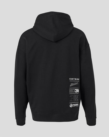Black pullover hoodie shown from the back, featuring white graphic text and logo prints on the lower back, set against a solid light gray background.