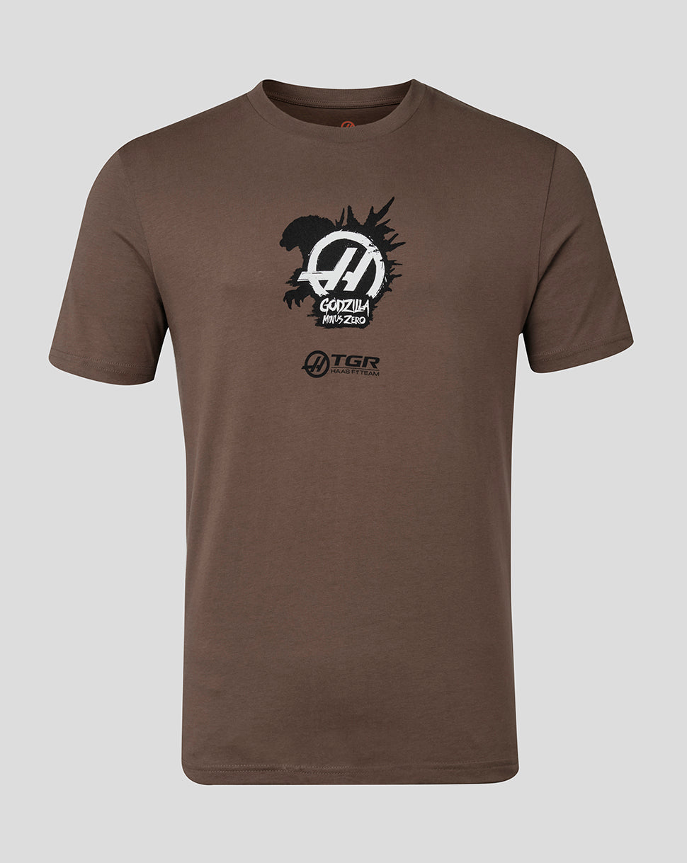 A brown short-sleeve crewneck t-shirt featuring a black and white graphic print on the chest with the text 'GODZILLA MINUS ZERO' and 'TGR' logos, displayed against a solid gray background.