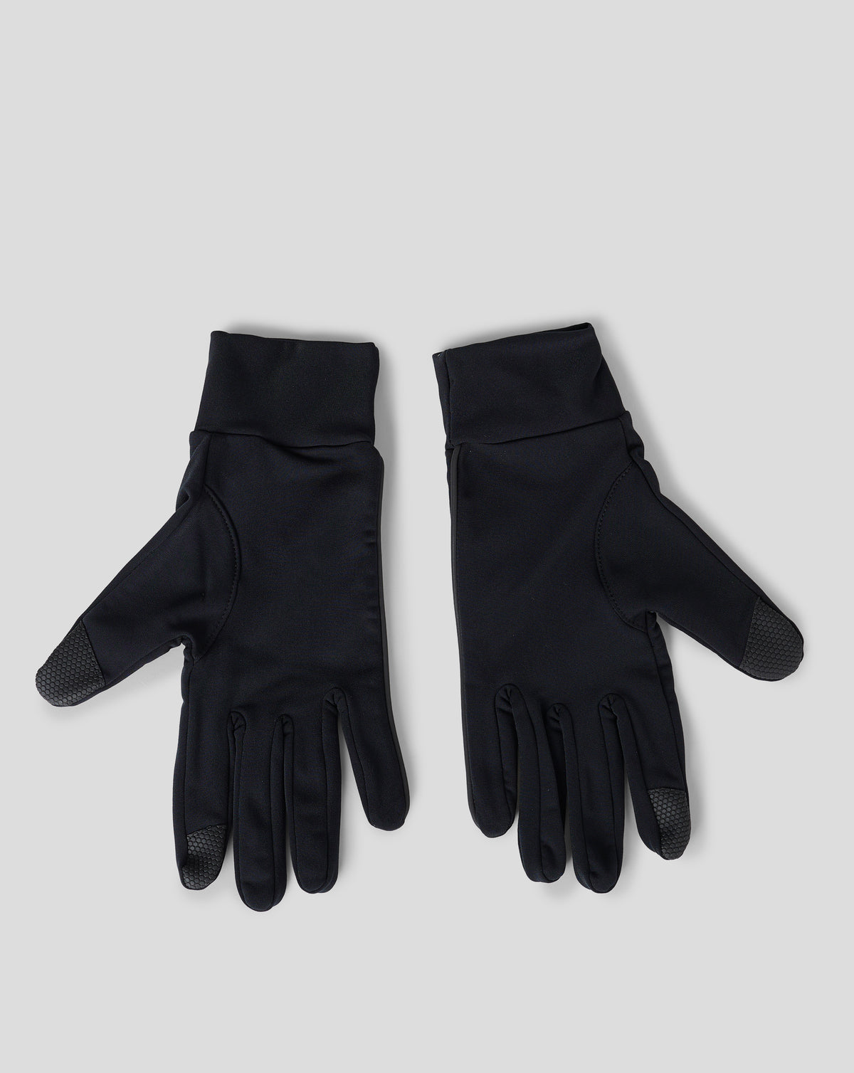 Pair of black gloves with textured palms laid on a light gray background