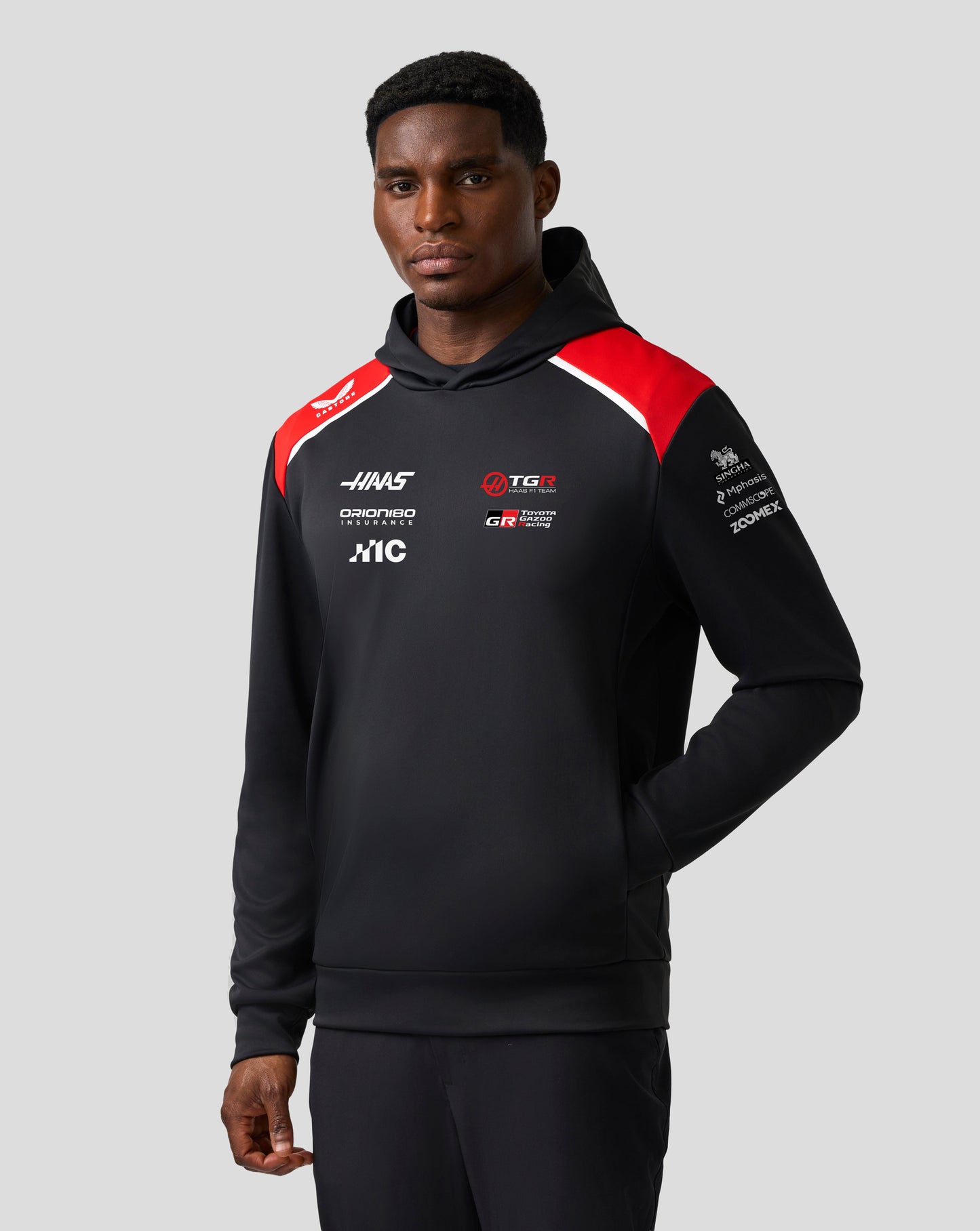 Person wearing a black hoodie with red and white accents on a gray background