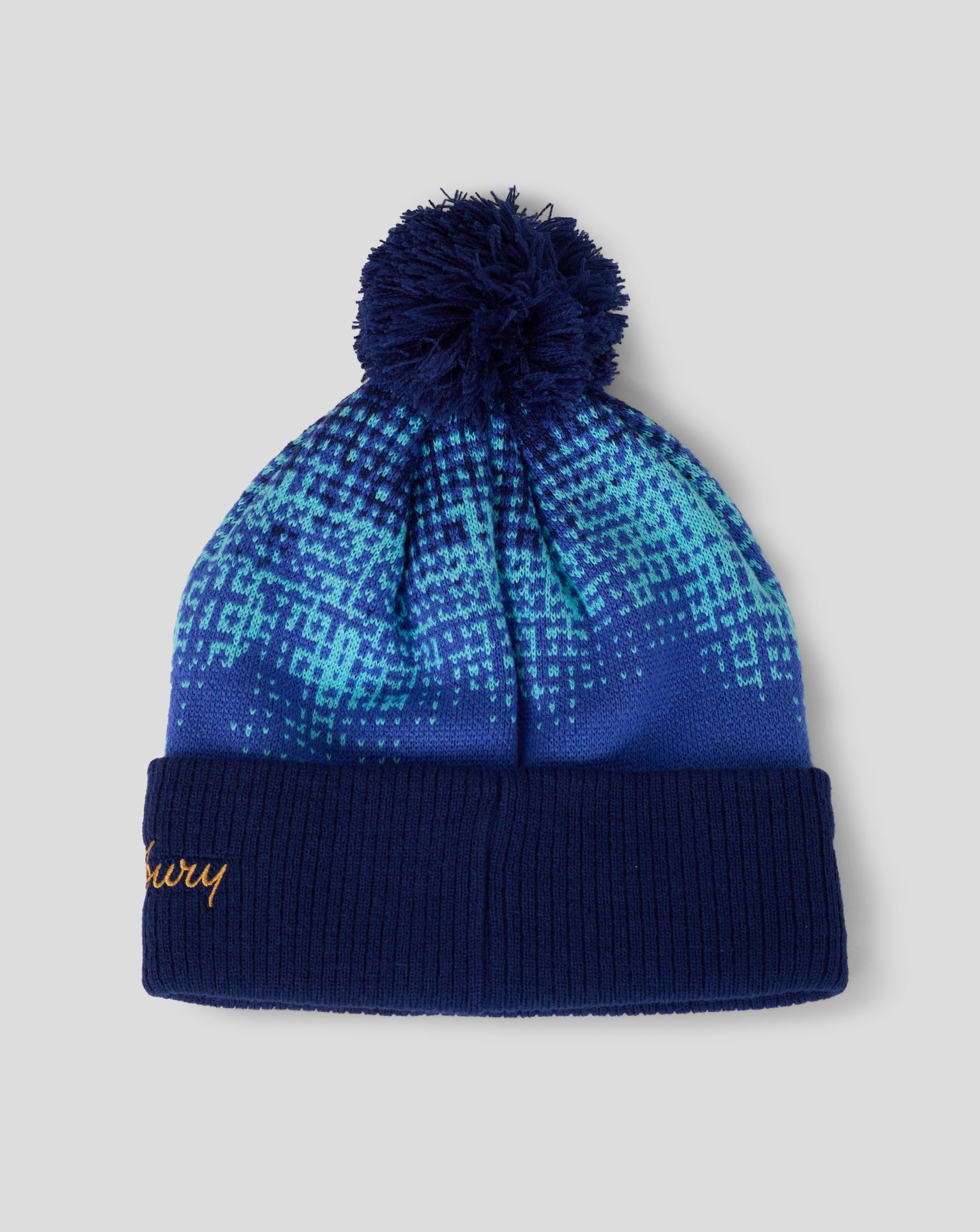 Blue patterned beanie with pom-pom on a light gray background
