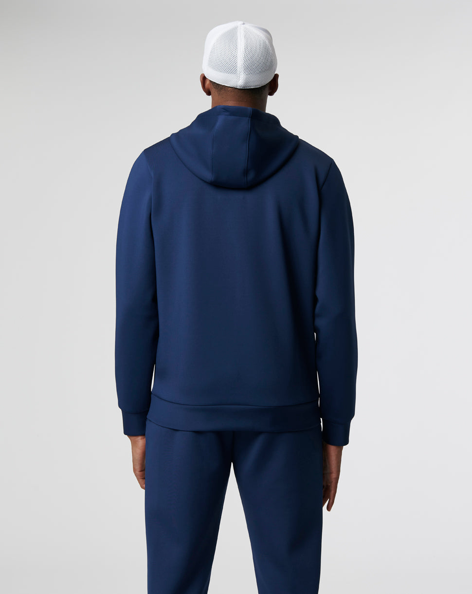 Back view of a model in navy Peacoat Flex Hoody 3.0 with matching pants and a white mesh cap