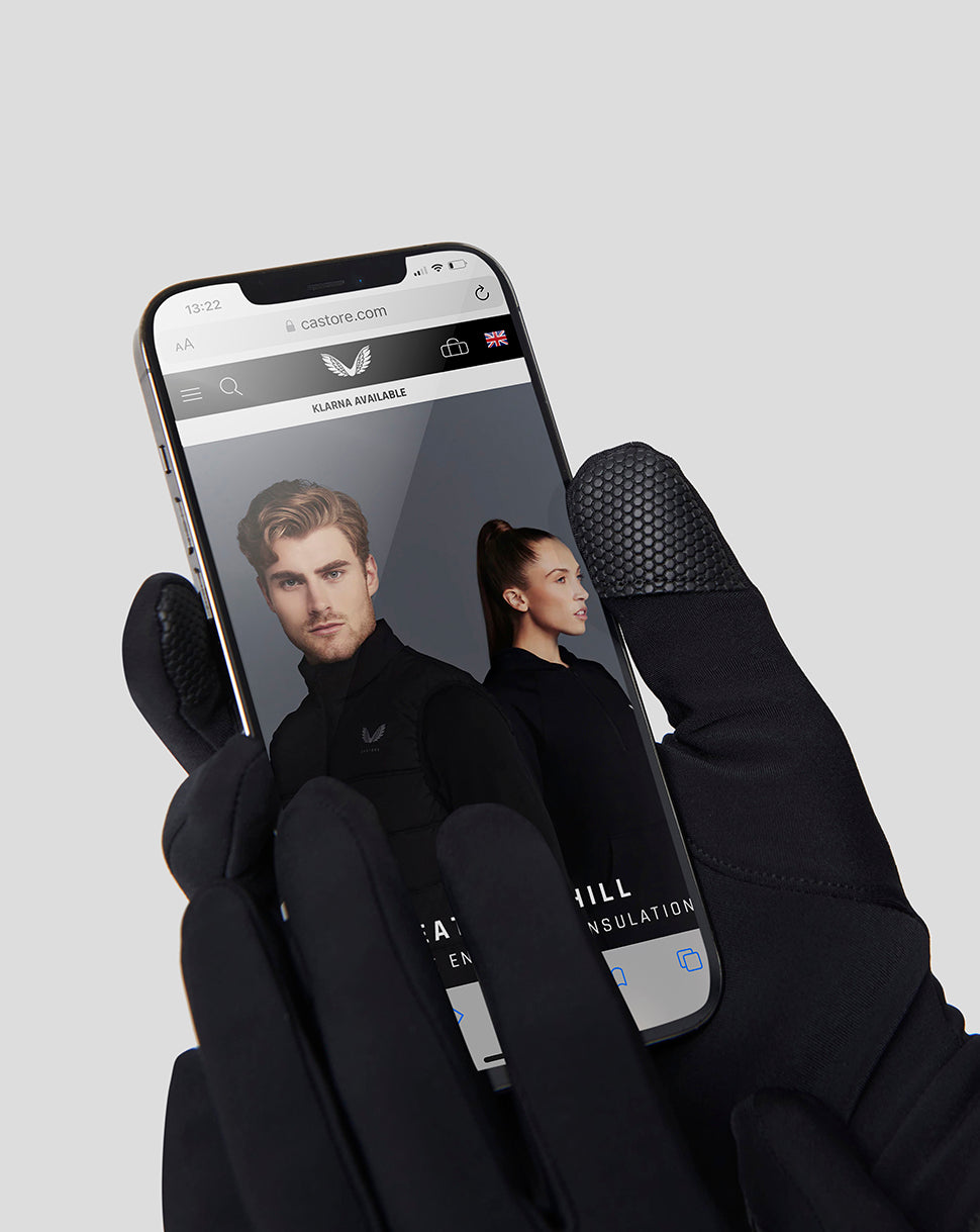 Black Onyx Performance Glove on hand holding a smartphone, showing touchscreen friendly fingertips and grip texture.