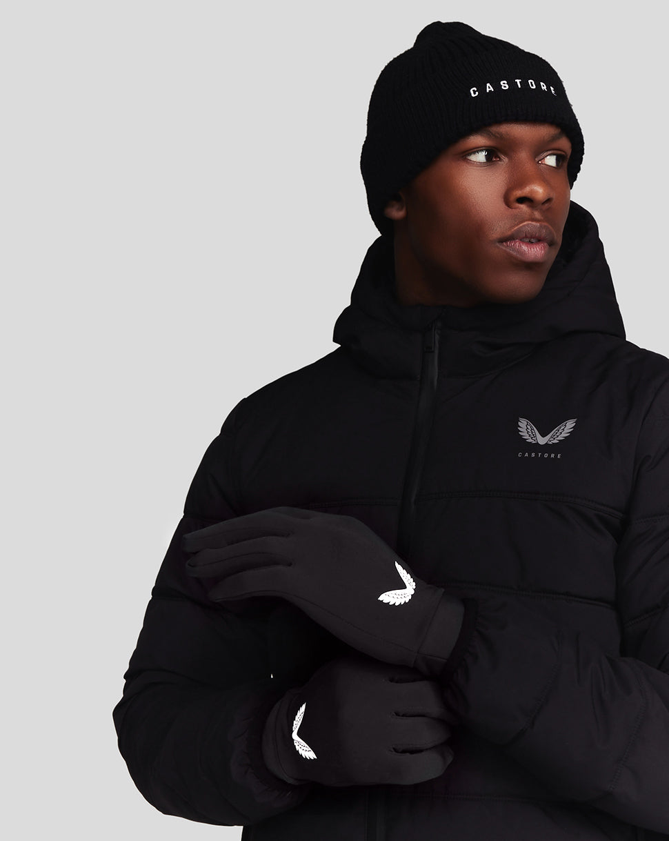 Male model wearing black Onyx Performance Gloves with white wing logo, paired with a black puffer jacket and knit beanie.
