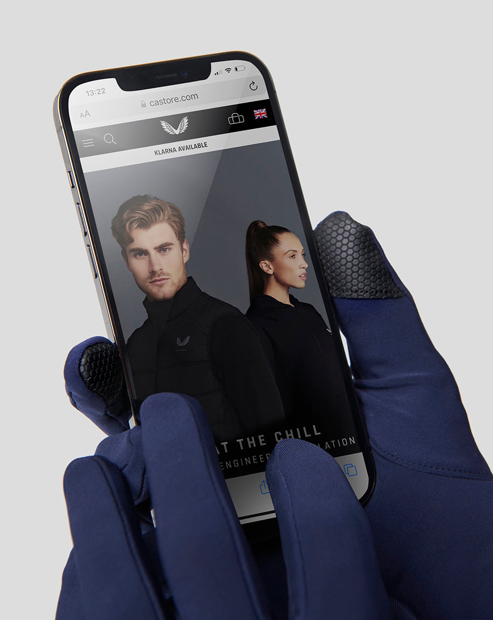 Navy Peacoat Performance Glove with touchscreen fingertips used to browse a smartphone site.